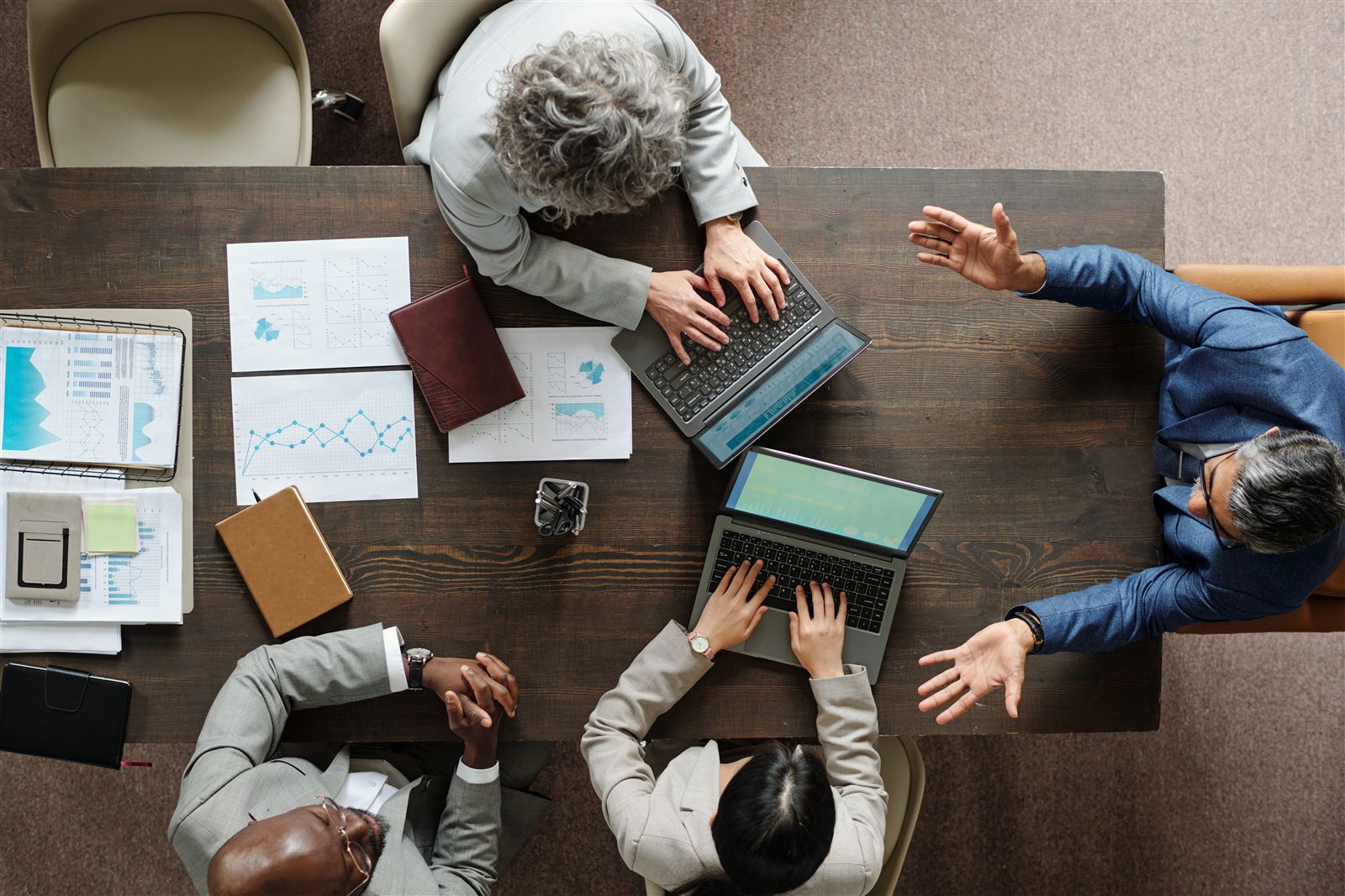 Professional meeting table with laptops, charts, and business documents